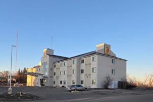 a large white building with a car parked in a parking lot at Super 8 by Wyndham Estevan in Estevan