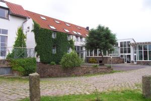 un bâtiment recouvert de lierre à côté d'une rue dans l'établissement Hotel Bördehof, à Barleben