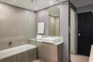 a bathroom with a sink and a tub and a mirror at Protea Hotel Fire & Ice! by Marriott Pretoria Menlyn in Pretoria