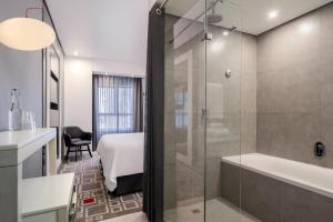 a bathroom with a shower and a sink and a tub at Protea Hotel Fire & Ice! by Marriott Pretoria Menlyn in Pretoria