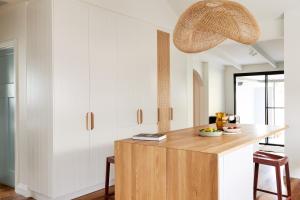 a kitchen with white cabinets and a wooden island at Bruns Surf Shack in Brunswick Heads +15 photos