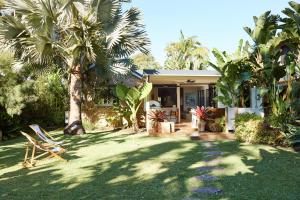 a house with a yard with chairs and palm trees at Bruns Surf Shack in Brunswick Heads