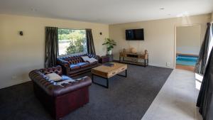 a living room with two leather couches and a tv at Tuscany Downs Estate in Darfield