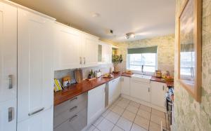 a kitchen with white cabinets and a window at Sheriff's Tower Cottage - West in Bishop Auckland +22 photos