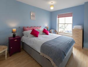 a blue bedroom with a large bed with red pillows at Sheriff's Tower Cottage - West in Bishop Auckland