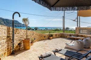 a patio with chairs and a stone wall at RIRIKA Beach Living, New Seaside Apartments in Plakias in Plakias