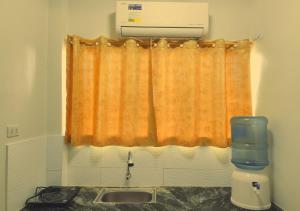 a kitchen with an orange curtain and a sink at Negradas Transient Inn-with Air-conditioning in Manolo Fortich +3 photos