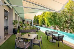 an outdoor patio with tables and chairs and a swimming pool at Protea Hotel Fire & Ice! by Marriott Pretoria Menlyn in Pretoria +55 photos