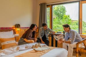 a group of people standing around a bed in a room at The Social Stays Tirthan in Bandal