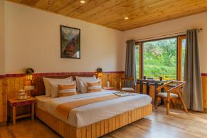 a bedroom with a bed and a desk and a window at The Social Stays Tirthan in Bandal