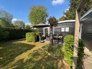a small backyard with a table and an umbrella at Chalet Wild Forest, knus chalet op de Veluwe met gratis parkeren in Putten