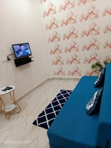 a living room with a blue couch and a tv at Kedarnath villa in Kakarmatha