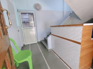a small room with a green chair and stairs at Narayan Guest House in Pune +29 photos