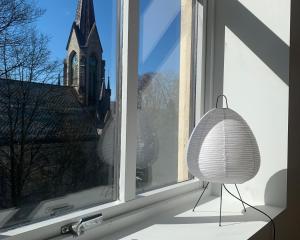 a room with a window with a lamp and a church at Cozy Scandinavian design apartment in Bergen