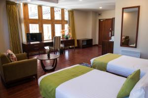 a hotel room with two beds and a desk at CityHotel, Thimphu in Thimphu