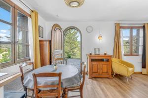a dining room with a table and chairs and windows at Le Domaines Des Thermes - T2 in Gap