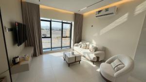 a living room with white furniture and a large window at Horizon Stay Nizwa in Firq