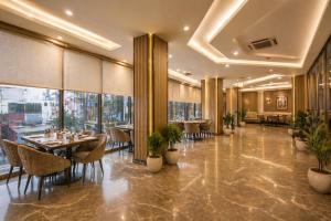 a dining room with tables and chairs and windows at Hotel Radiance Park Delhi Airport in New Delhi