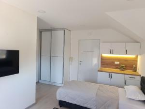 a bedroom with a bed and a kitchen with white cabinets at VA vikendica Tesanj in Tešanj