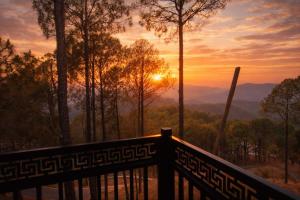 a view of the sunset from a wooden railing at The Whistling Pine Homestay With Natural Swimming Pool in Lansdowne