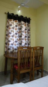 a dining room table with two chairs and a curtain at Moon Hug Boutique Beach House in Auroville