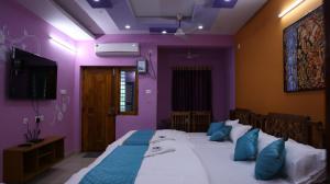 a bedroom with a large bed with purple walls at Moon Hug Boutique Beach House in Auroville
