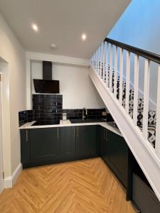 a kitchen with black cabinets and a staircase at Peaceful Self-Contained Apartment in Beckenham