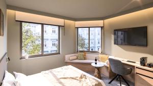 a bedroom with a bed and a tv and two windows at Nixon Downtown, a member of Nixon Hotels in Athens