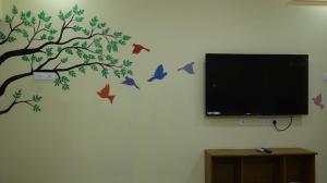a tree with birds on a wall with a tv at Moon Hug Boutique Beach House in Auroville