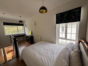 a bedroom with a bed and a couch and two windows at Peaceful Self-Contained Apartment in Beckenham +20 photos