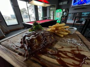 a steak and french fries on a wooden cutting board at Guiding Star Motel & Hotel in Brooklyn
