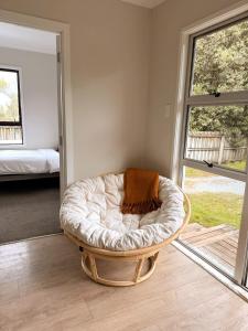 a dog bed sitting in a room with a window at The Bach at One Tree Point in One Tree Point