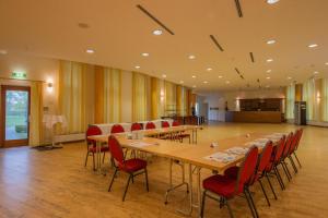 a large conference room with a long table and red chairs at SeeHotel Großräschen in Großräschen +99 photos