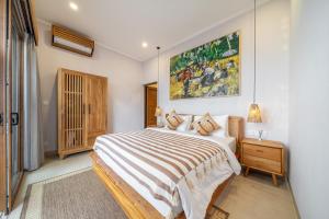 a bedroom with a bed and a painting on the wall at Cassandra Villas - Tropical Private Pool Escape near Beach in Sanur