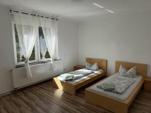 two beds in a room with two windows at Pension Lindenhof Drabsch in Neuzelle