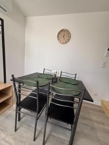 a dining room table with two chairs and a clock on the wall at Chez Mimi in Maubert-Fontaine +4 photos