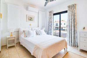 a white bedroom with a bed and a window at 4 Bedroom Villa With Private Pool in Maroni