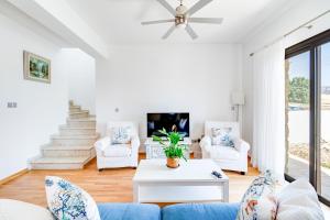 a living room with a blue couch and white chairs at 4 Bedroom Villa With Private Pool in Maroni