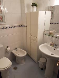 Baño blanco con aseo y lavamanos en Apartamento Venecia Arenal en Sevilla