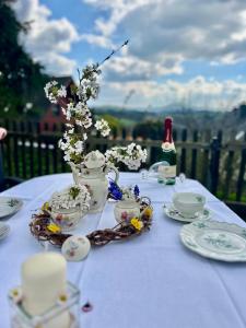 a table with a tea set with flowers and a bottle of wine at Fewo Pöhlbergblick Wolkenstein in Wolkenstein