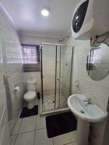 a bathroom with a shower and a toilet and a sink at One Bedroom Apartment B in Kempton Park +5 photos