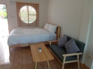 a bedroom with a bed and a couch and a table at MUJISTAY Hotel มูจิสเตย์โฮเทล in Ban Non Than