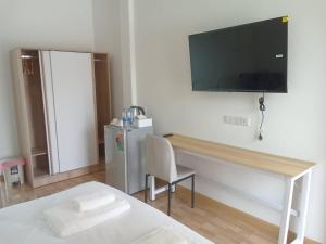 a bedroom with a bed and a desk with a television on the wall at MUJISTAY Hotel มูจิสเตย์โฮเทล in Ban Non Than