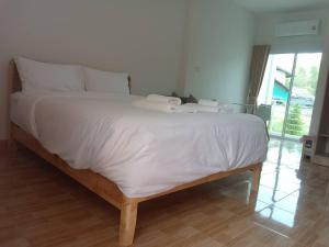 a large bed with white sheets and pillows on it at MUJISTAY Hotel มูจิสเตย์โฮเทล in Ban Non Than