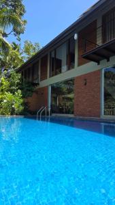 a large blue swimming pool in front of a building at Moonstone herbal villa in Balapitiya +20 photos