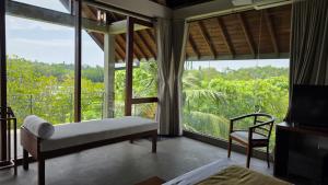 a bedroom with a bed and a chair and a large window at Moonstone herbal villa in Balapitiya