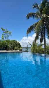 a blue swimming pool with a palm tree in the background at Moonstone herbal villa in Balapitiya