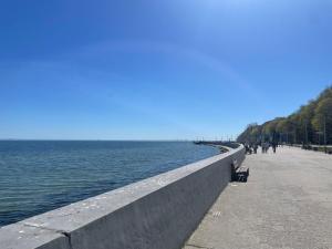 people walking on a sidewalk next to a body of water at Gdynia Bulwar in Gdynia +9 photos
