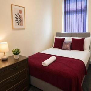 a bedroom with a bed with red sheets and a window at The Range Nestled Nook in Manchester