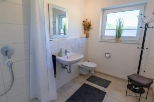 a white bathroom with a sink and a toilet at Ferienhaus Aura in Bodman-Ludwigshafen +38 photos
